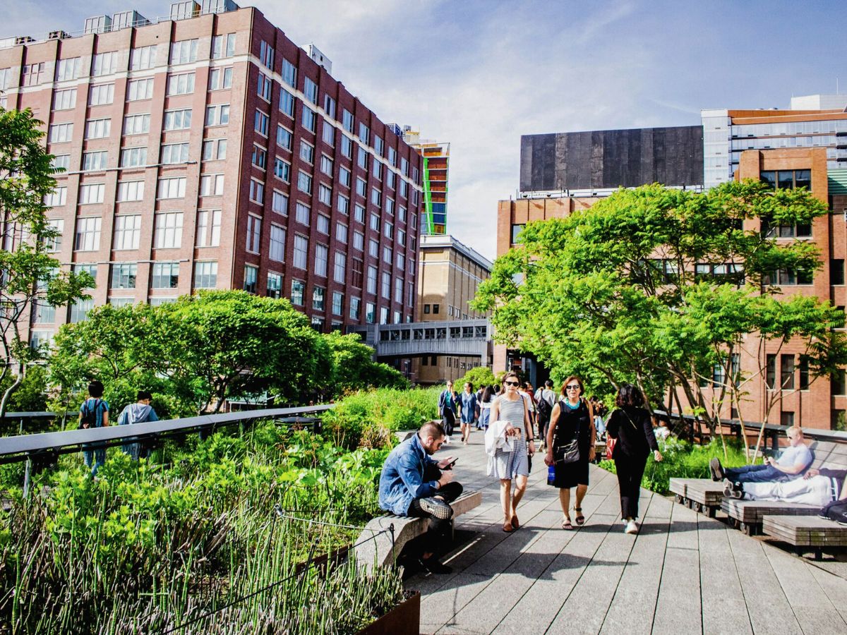 People walking along a landscaped urban park path called the High Line Trail.